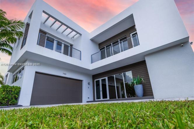 A modern two-story house features a white exterior, a garage, and balconies with metal railings — 7480 NW 99th Ave, Doral FL 33178, DORAL, FL