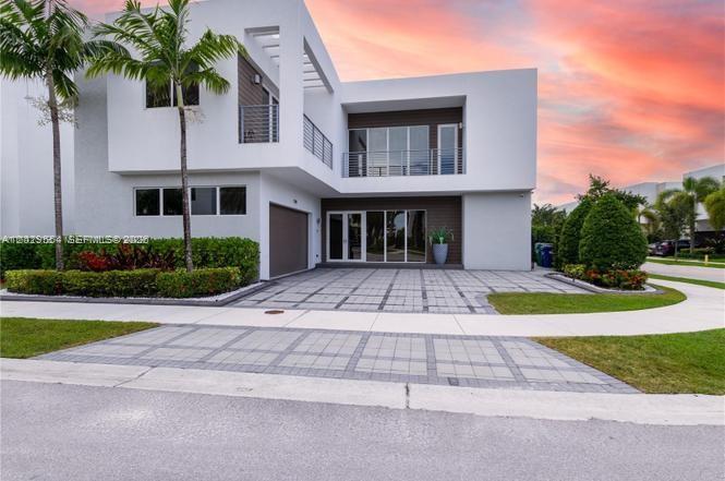 A modern two-story house features white exterior walls, a paved driveway, and palm trees — 7480 NW 99th Ave, Doral FL 33178, DORAL, FL