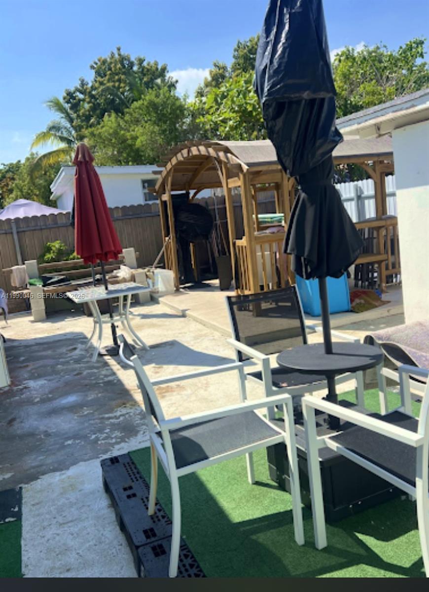 A backyard patio features two outdoor dining sets with umbrellas and a wooden gazebo — 2373 NW 33rd St, Miami FL 33142, MIAMI, FL