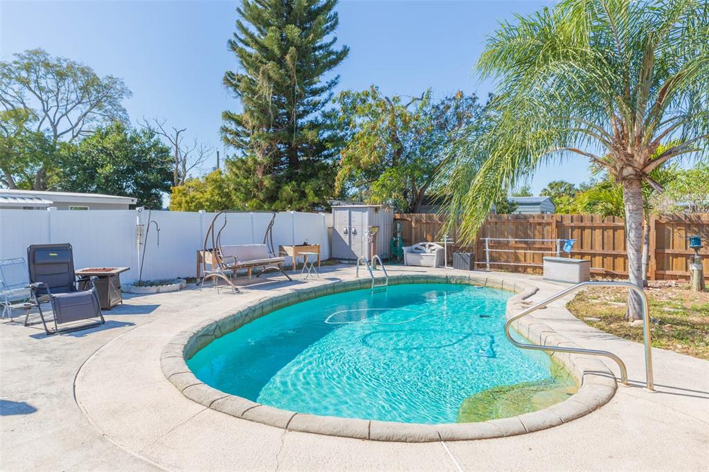 A backyard features an in-ground swimming pool surrounded by a concrete patio and fencing — 4102 W FAIRVIEW HEIGHTS, TAMPA, FL