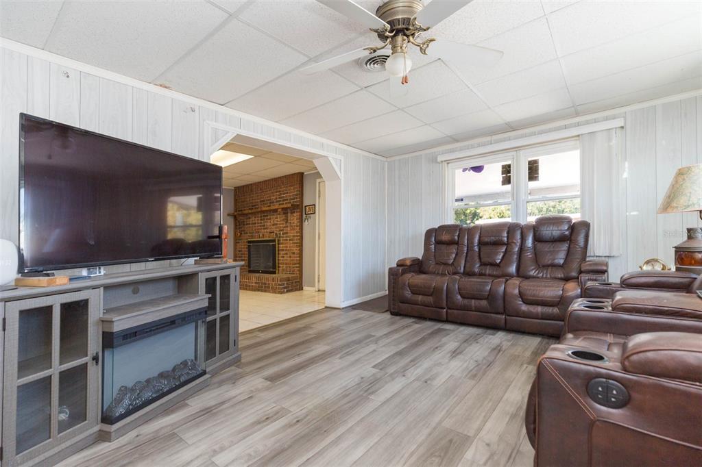 A living room features wood-look flooring, a brown leather sofa, and a television console — 4102 W FAIRVIEW HEIGHTS, TAMPA, FL