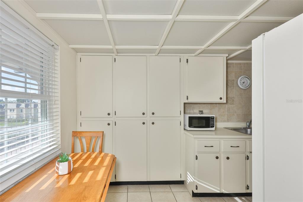A kitchen features white cabinets, a microwave, a small sink, and a wooden dining table — 8703 BARDMOOR BOULEVARD UNIT 303, SEMINOLE, FL