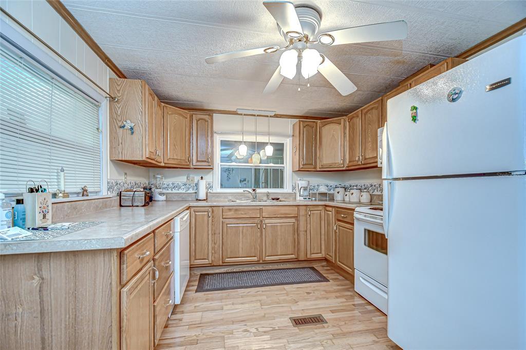 A kitchen with light wood cabinets, laminate countertops, white appliances, and a ceiling fan — 39443 ELGIN DRIVE, ZEPHYRHILLS, FL
