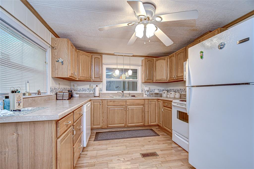 A kitchen with light wood cabinets, white appliances, laminate countertops, and a ceiling fan — 39443 ELGIN DRIVE, ZEPHYRHILLS, FL