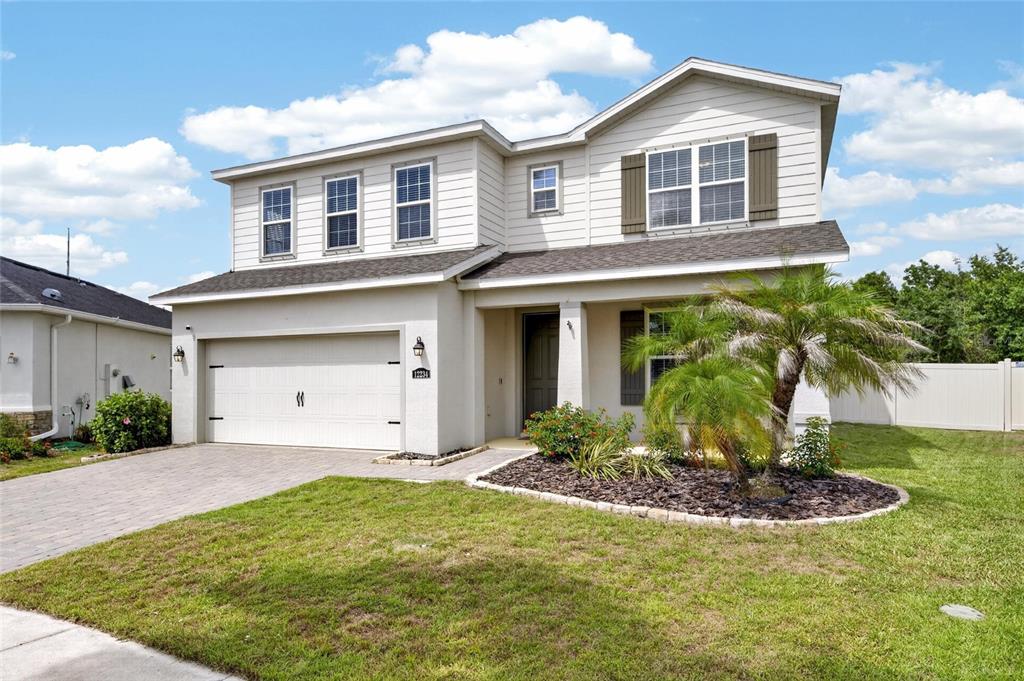 A two-story suburban house with beige siding, a two-car garage, and a front palm tree — 12234 BLUE PACIFIC DRIVE, RIVERVIEW, FL