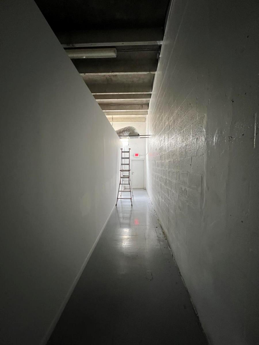 A narrow hallway with white walls, a concrete floor, and a ladder leading to a door — 3335 NW 74th Avenue # 3335, Miami FL 33122, MIAMI, FL