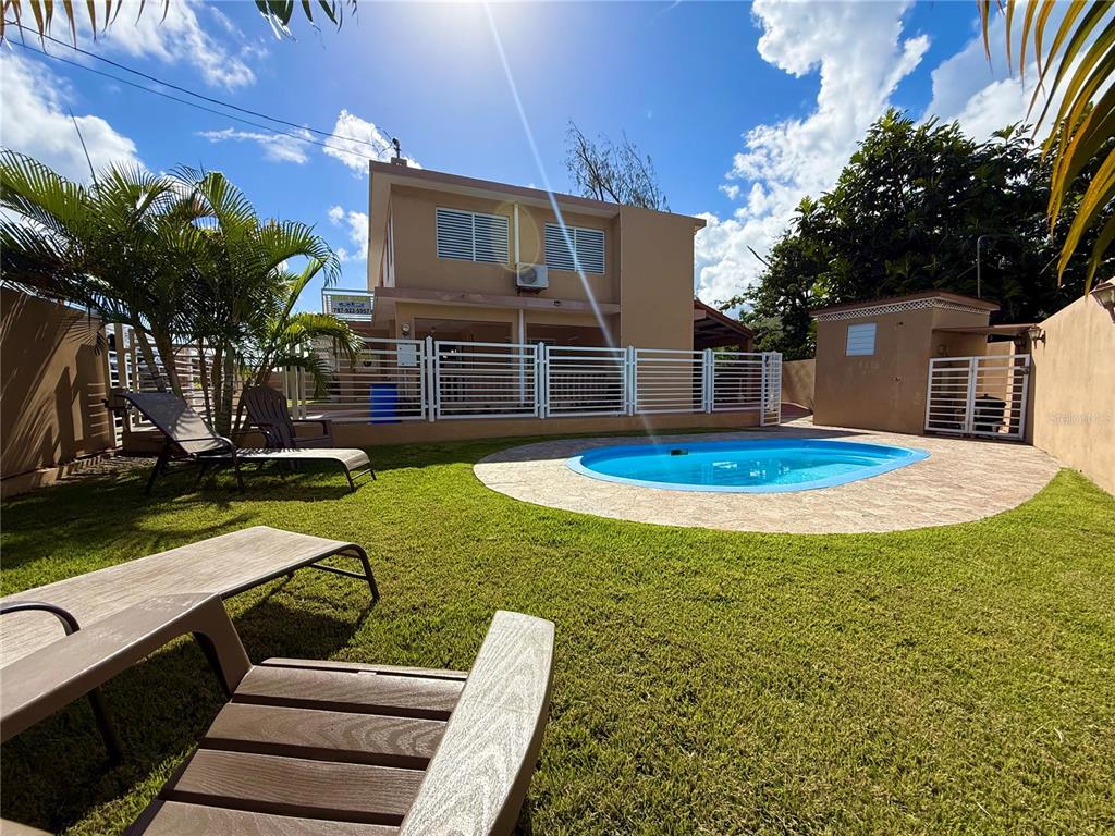 A backyard features a small swimming pool, a grassy lawn, and a two-story house — carr #3 JUST 1 MINUTE BEACH, PATILLAS, PR