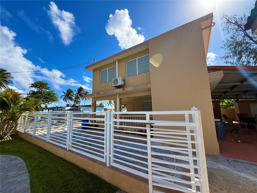 A two-story tan house features a white fence, a covered patio, and louvered windows — carr #3 JUST 1 MINUTE BEACH, PATILLAS, PR
