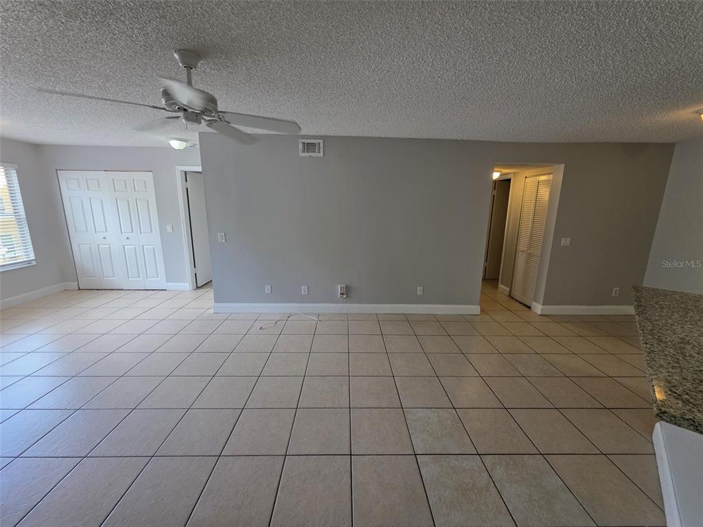 An empty room features light-colored tile flooring, a ceiling fan, and gray walls — 4532 COMMANDER DRIVE UNIT 2127, ORLANDO, FL