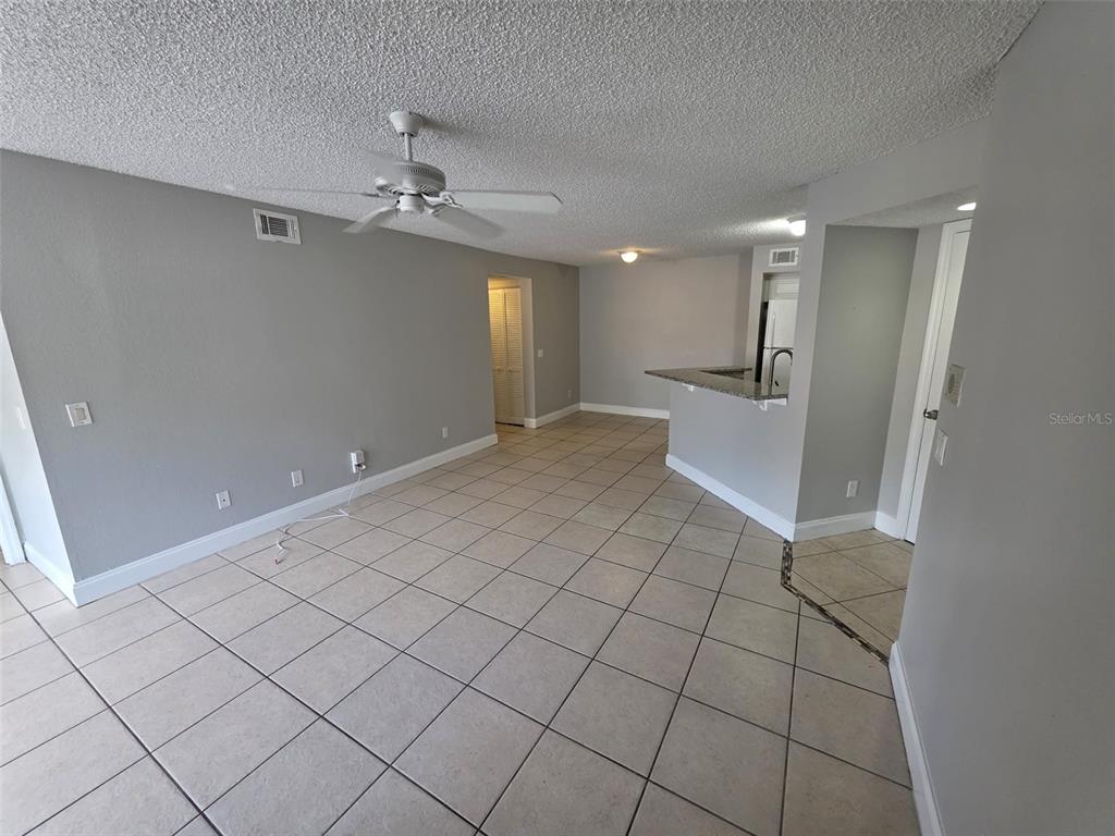 An open-concept living area features light gray walls, tile flooring, and a ceiling fan — 4532 COMMANDER DRIVE UNIT 2127, ORLANDO, FL