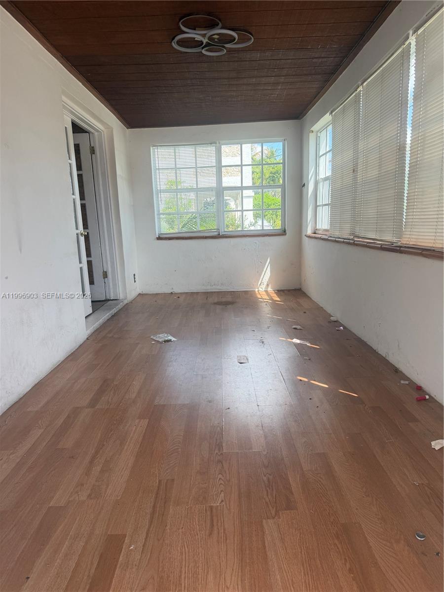 This sunroom features wood-look flooring, a wood-paneled ceiling, and multiple windows with blinds — 634 SW 10th Ave, Miami FL 33130, MIAMI, FL
