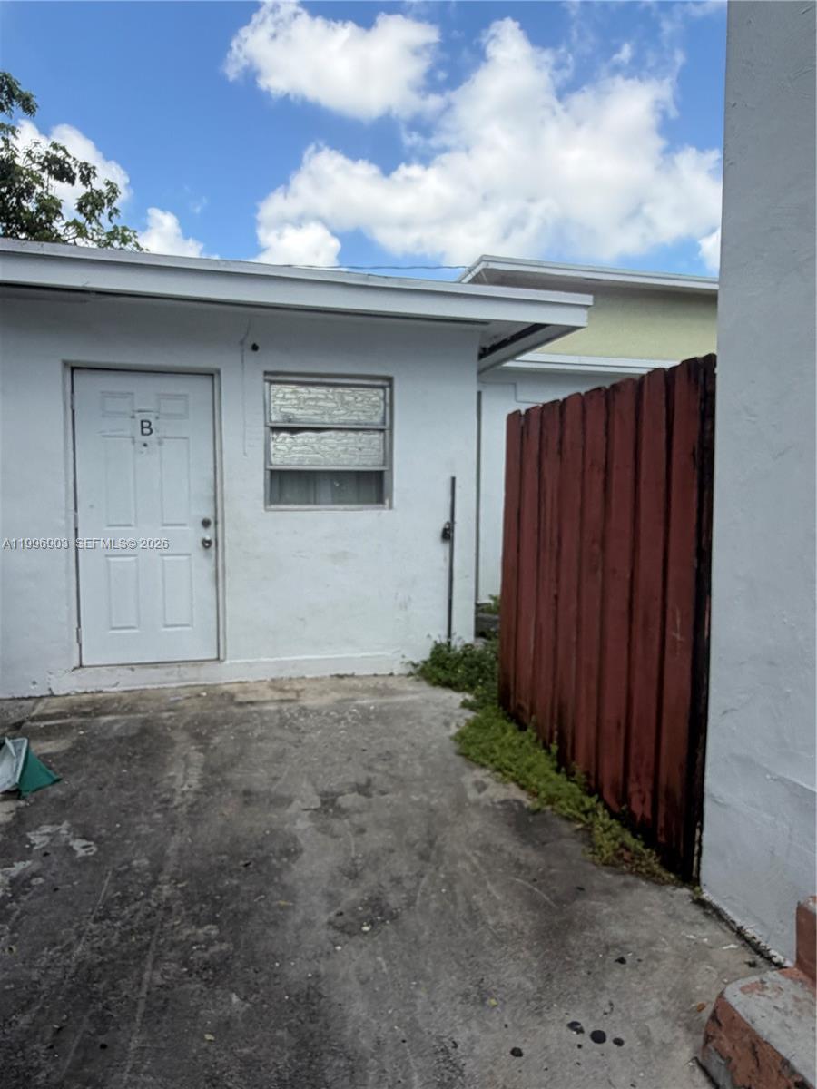 A white exterior wall features a door labeled B, a window, and a wooden fence — 634 SW 10th Ave, Miami FL 33130, MIAMI, FL