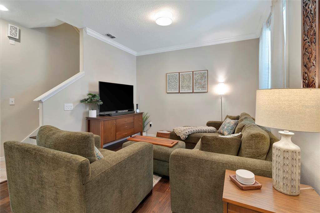 A living room features olive green furniture, a wooden media console, and wall art — 1207 ALSTON BAY BOULEVARD, APOPKA, FL