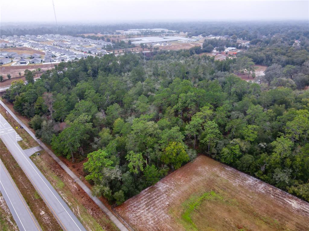 An aerial view shows a wooded lot adjacent to a paved road and cleared land — W RHODE ISLAND AVENUE, ORANGE CITY, FL