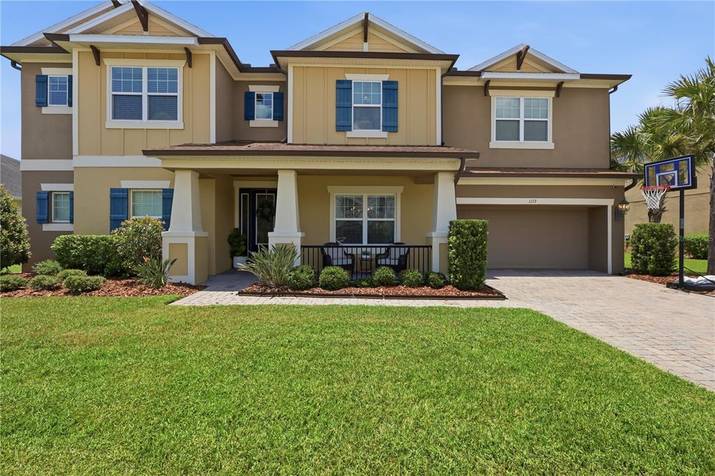 A two-story suburban house with a tan exterior, blue shutters, and a front porch — 1177 FIELDSTONE CIRCLE, OVIEDO, FL