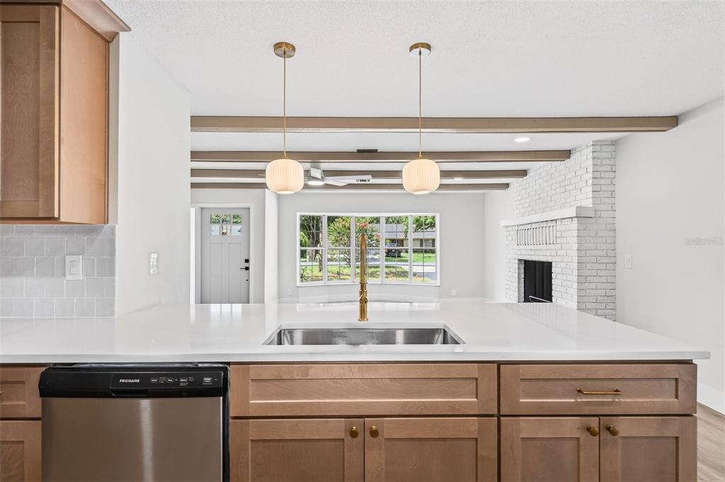A kitchen island with a stainless steel sink faces a living room with exposed beams — 17901 PALM STREET, UMATILLA, FL