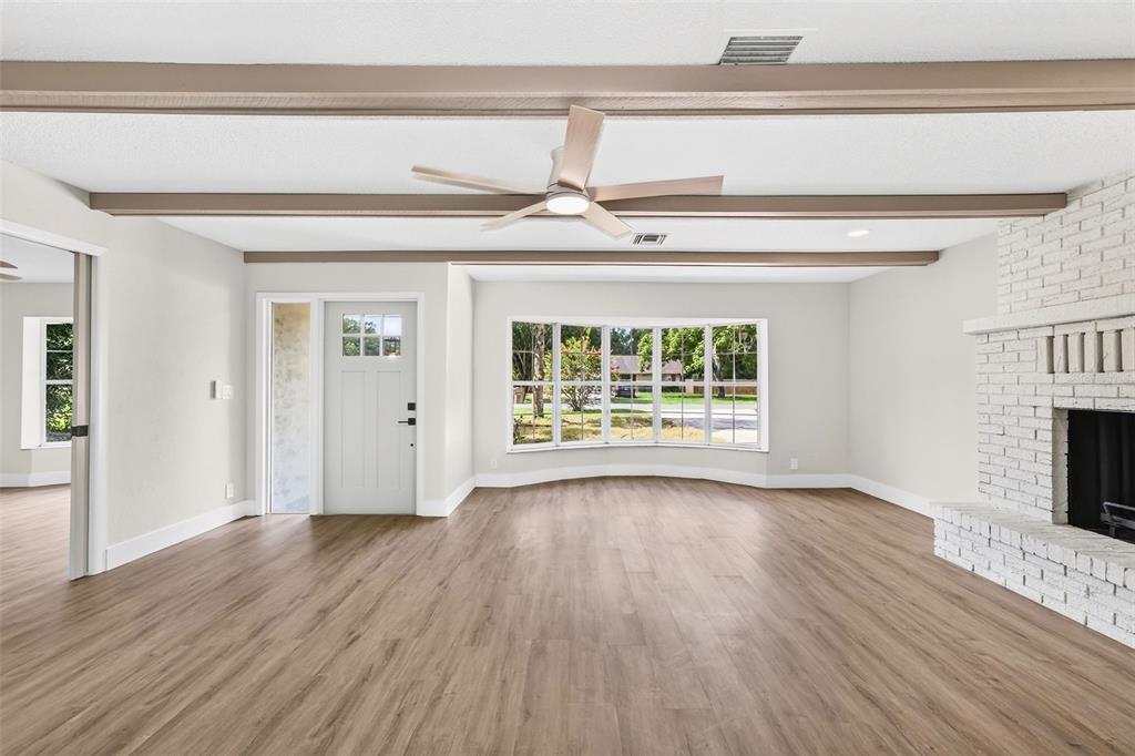 A living room with light wood flooring, a white brick fireplace, and a ceiling fan — 17901 PALM STREET, UMATILLA, FL