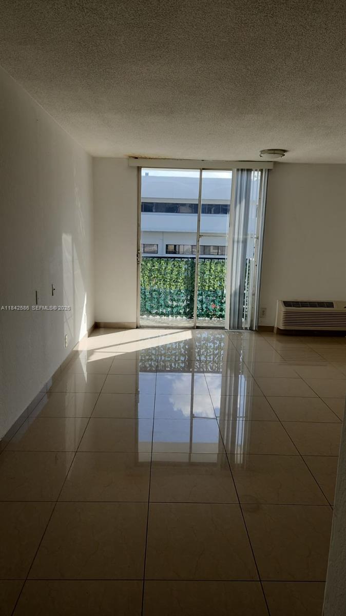 An empty room with light-colored tile flooring, white walls, and a sliding glass door — 16450 NW 2nd Ave # 206, Miami FL 33169, MIAMI, FL