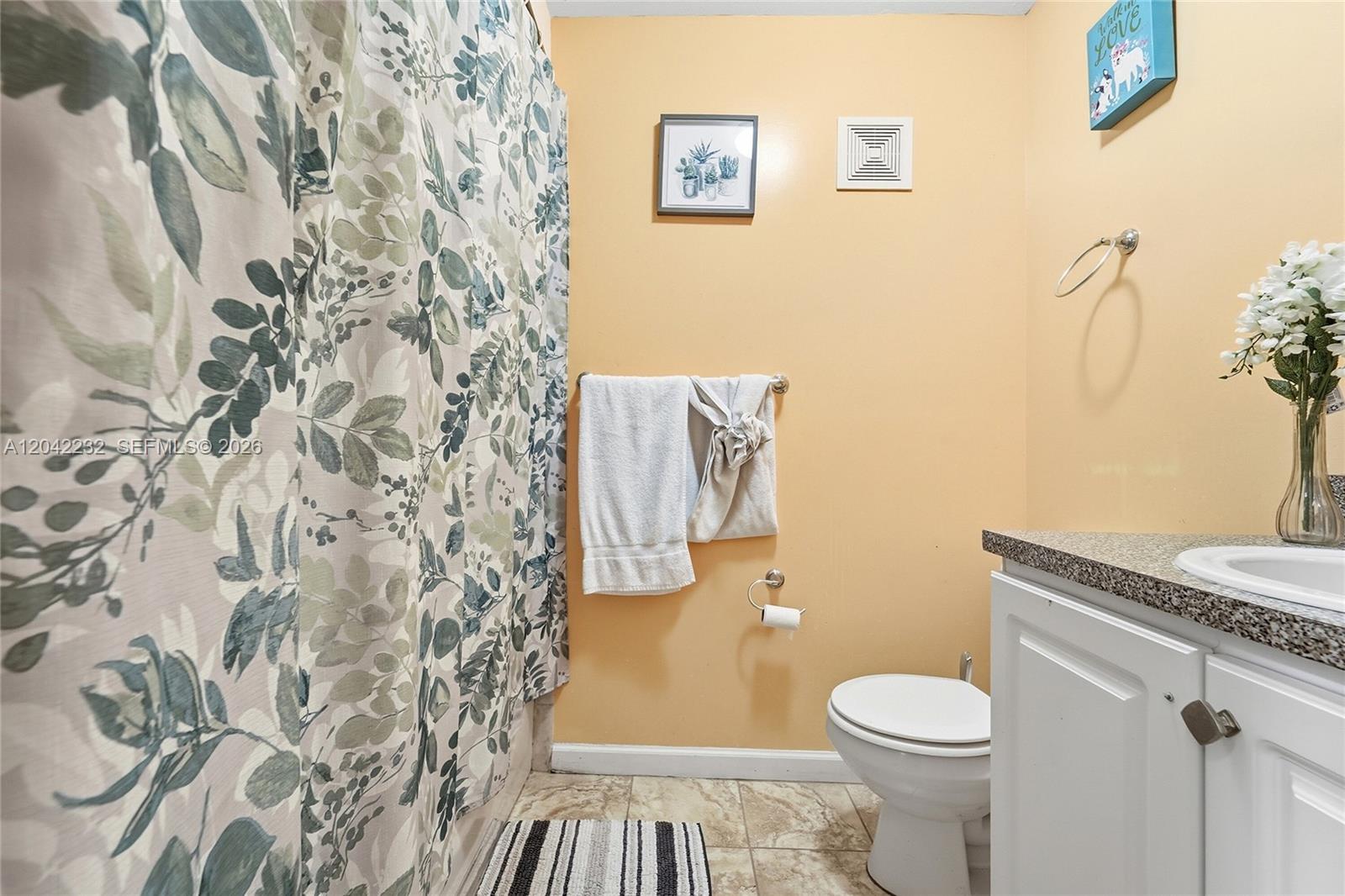 A bathroom features a floral shower curtain, peach walls, a white vanity, and a toilet — 2974 NW 55th Ave # 2B, Lauderhill FL 33313, LAUDERHILL, FL
