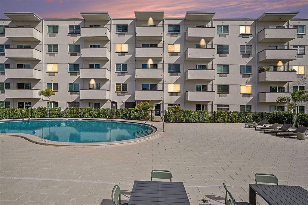 A multi-story apartment building stands behind a swimming pool and a paved patio area — 406 S CEDAR AVENUE UNIT 505, TAMPA, FL