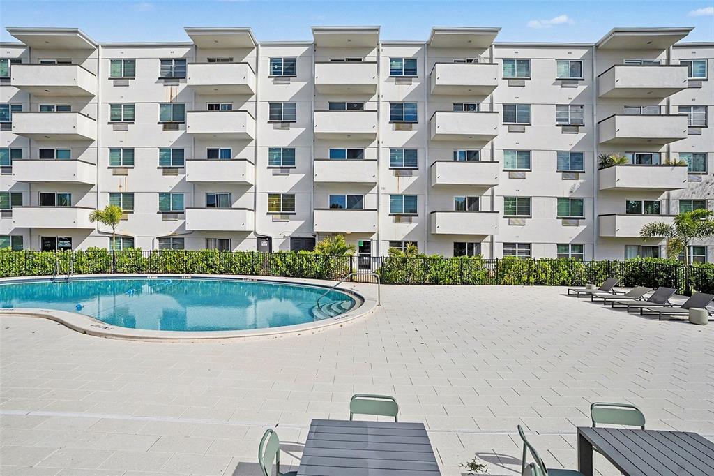 A multi-story apartment building exterior features balconies overlooking a swimming pool and paved patio area — 406 S CEDAR AVENUE UNIT 505, TAMPA, FL
