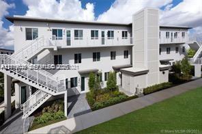 An exterior view of a multi-story apartment building with white siding and an outdoor staircase — DORAL, FL