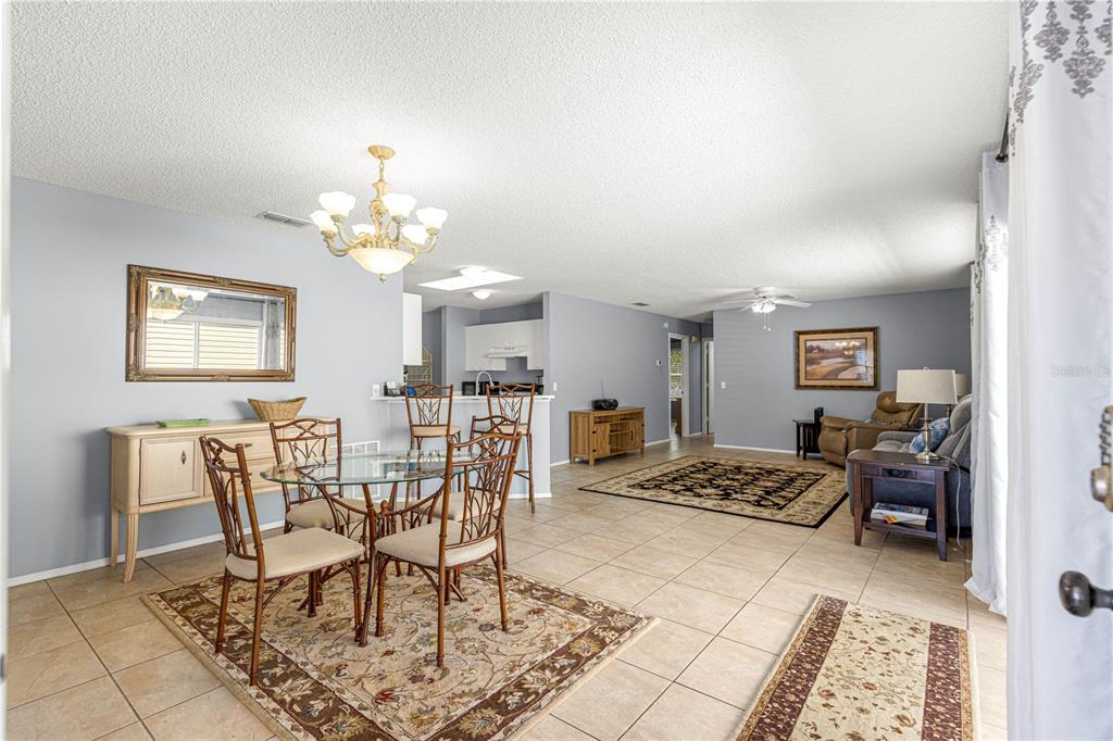 A dining area with a glass table and chairs opens into a living room — 2140 ESTEVEZ DRIVE, LADY LAKE, FL