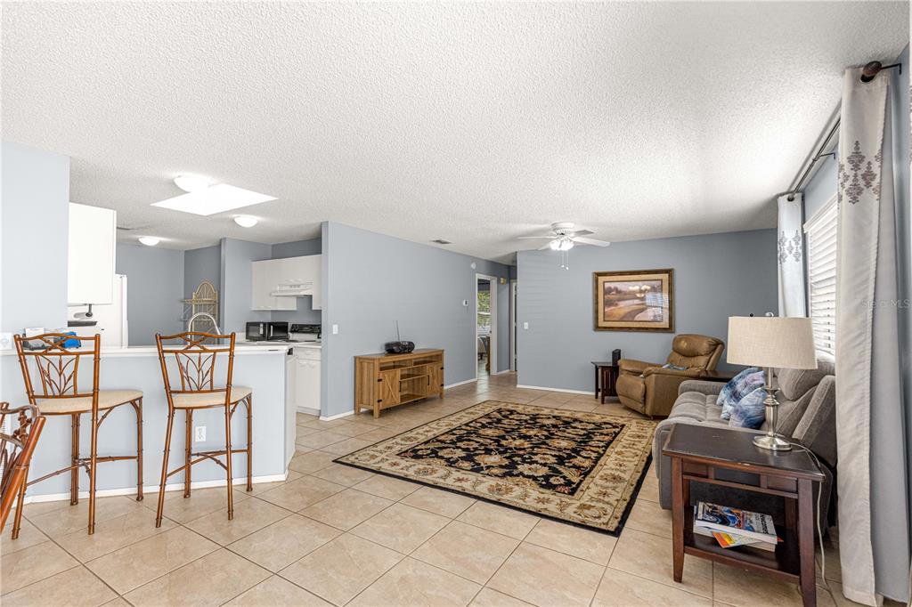 A living room with tile floors, a kitchen bar, and a sofa faces a television stand — 2140 ESTEVEZ DRIVE, LADY LAKE, FL