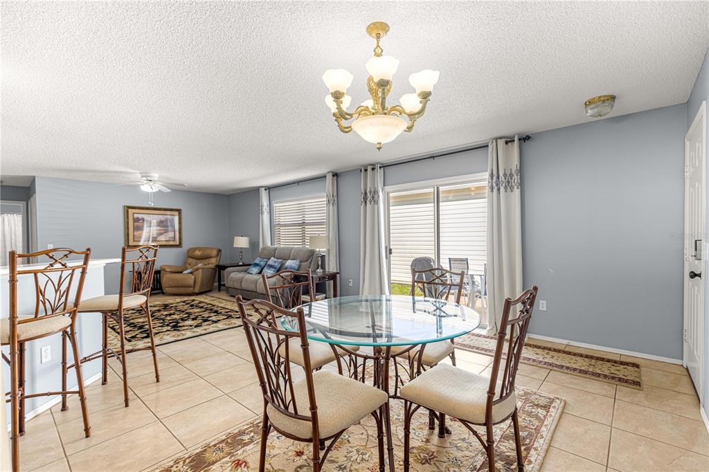 A dining area with a glass table and chairs sits adjacent to a living room — 2140 ESTEVEZ DRIVE, LADY LAKE, FL