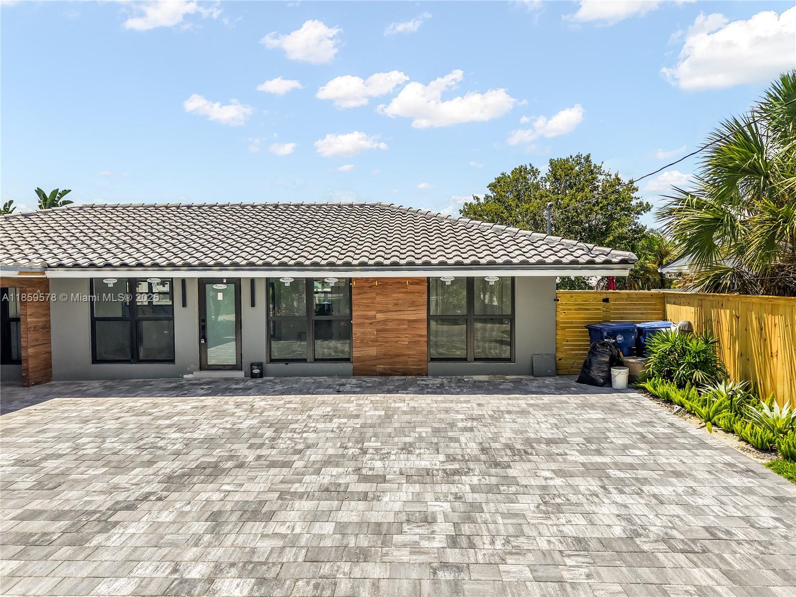 The exterior of a house features a tiled roof, gray walls, wood accents, and paver driveway — 2417 NE 18th Ave, Wilton Manors FL 33305, WILTON MANORS, FL