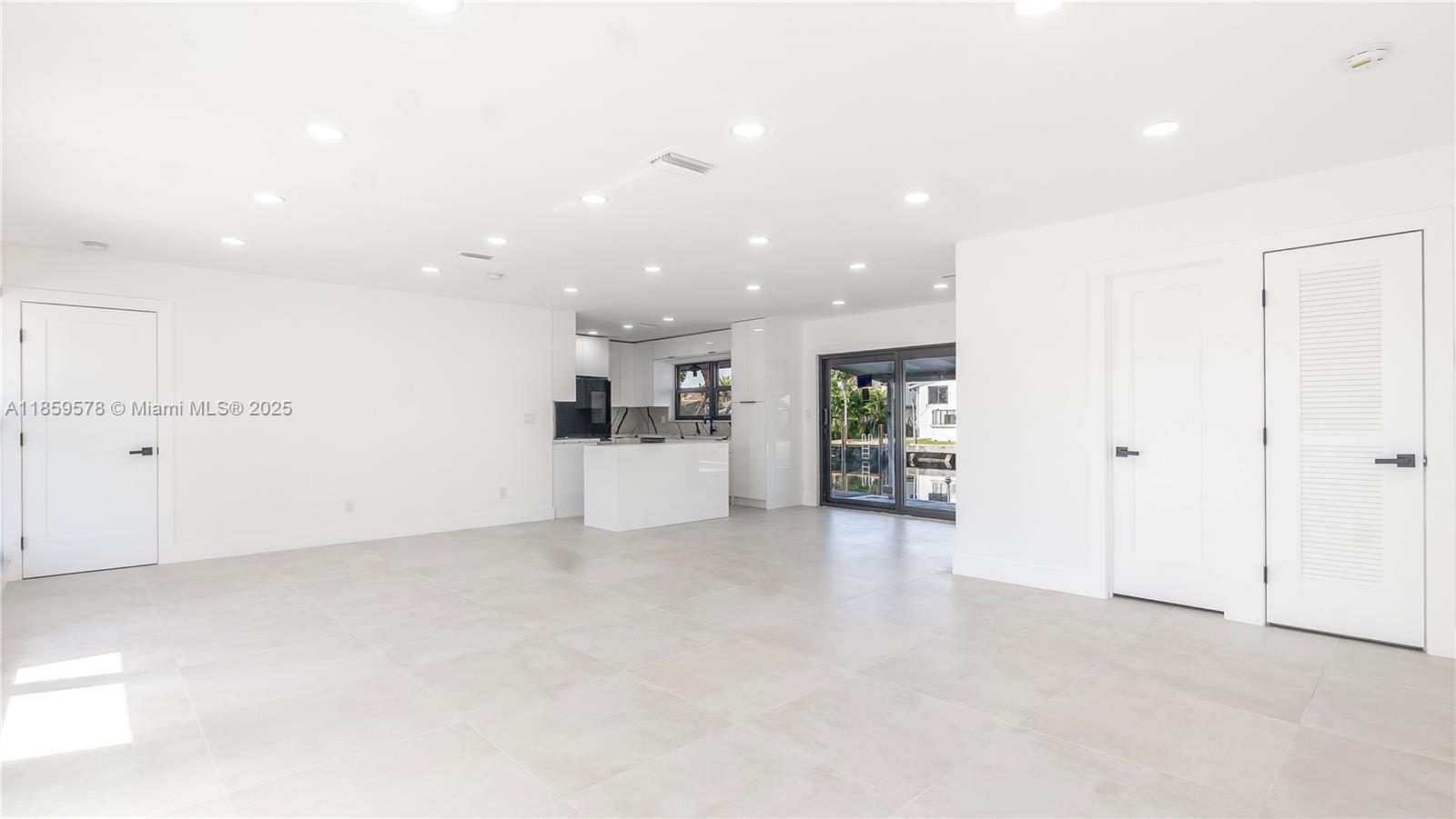 A bright, open-concept room features white walls, light tile flooring, recessed lighting, and a kitchen — 2417 NE 18th Ave, Wilton Manors FL 33305, WILTON MANORS, FL