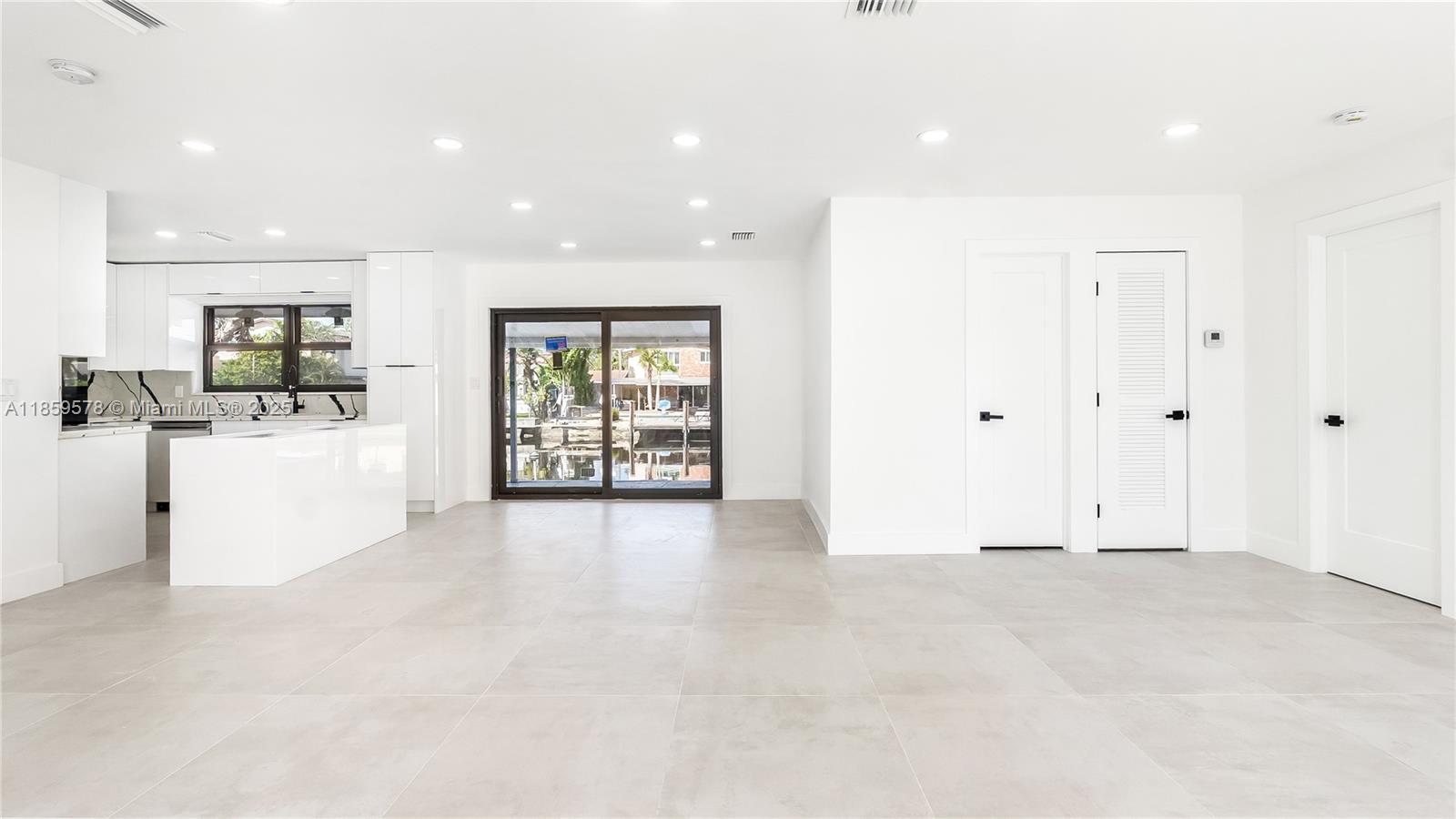 A modern, white-toned open-concept kitchen and living area features large light-colored floor tiles — 2417 NE 18th Ave, Wilton Manors FL 33305, WILTON MANORS, FL