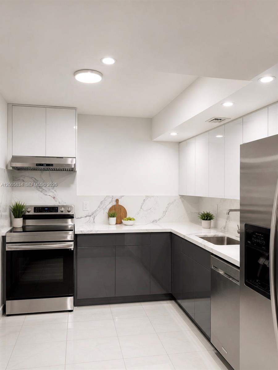 A modern kitchen features white upper cabinets, dark grey lower cabinets, and marble-patterned countertops — 701 Three Islands Blvd # 120, Hallandale Beach FL 33009, HALLANDALE BEACH, FL