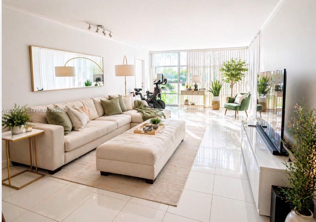 A bright living room features a beige sectional sofa, large ottoman, tile floors, and floor-to-ceiling windows — 701 Three Islands Blvd # 120, Hallandale Beach FL 33009, HALLANDALE BEACH, FL