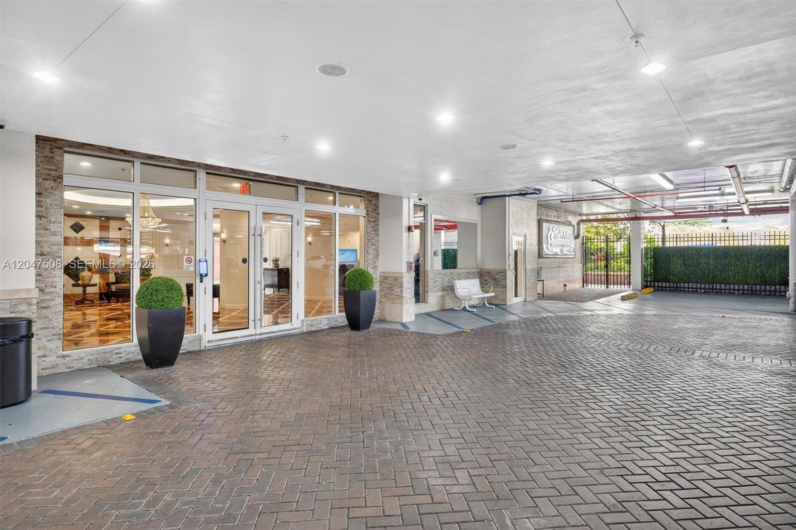 A paved driveway leads to the glass-fronted entrance of a building with stone accents — 3232 SW Coral Way # 903, Miami FL 33145, MIAMI, FL