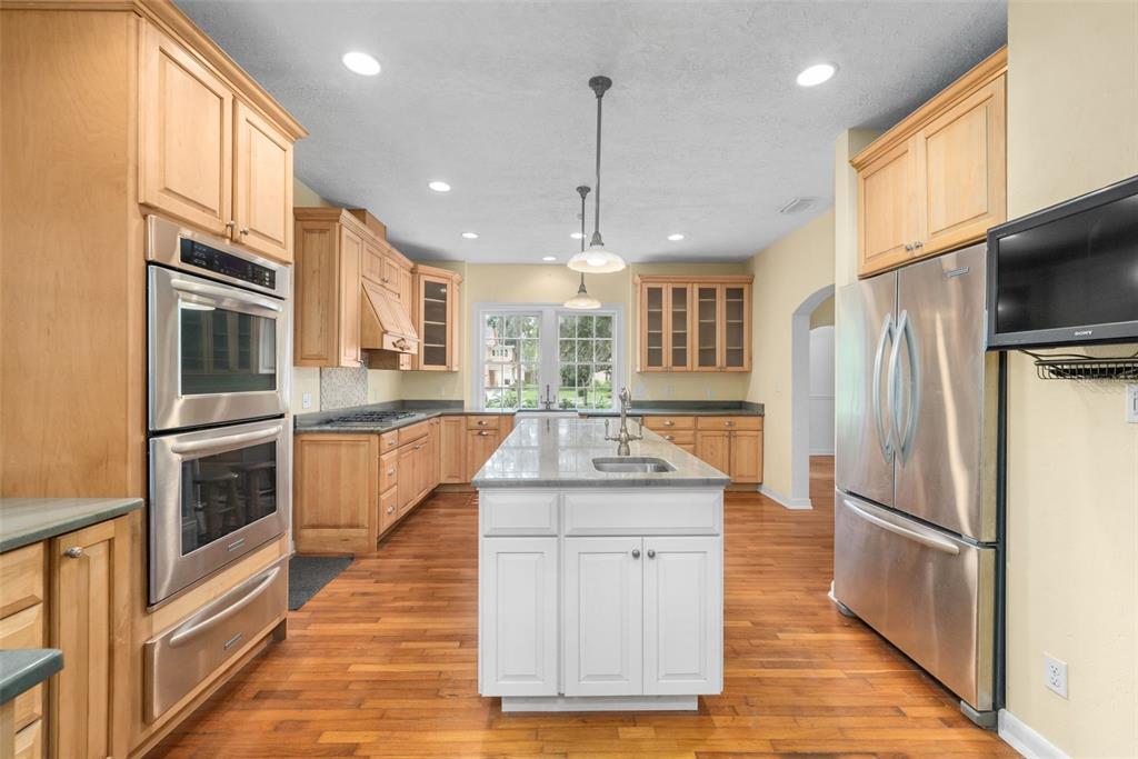 A kitchen features light wood cabinetry, a white center island, and stainless steel appliances — 717 NE BOULEVARD, GAINESVILLE, FL
