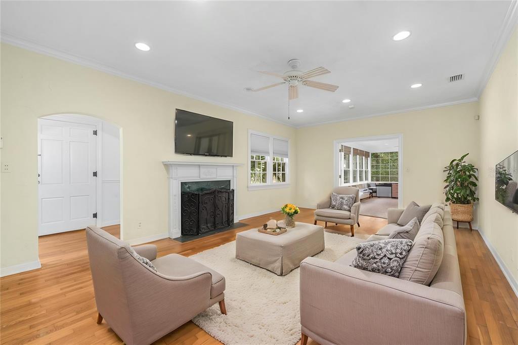 A living room features a fireplace, a ceiling fan, hardwood floors, and neutral furniture — 717 NE BOULEVARD, GAINESVILLE, FL