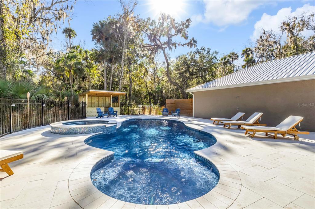 A swimming pool and hot tub sit on a patio beside a house and trees — 2760 PEARL LAKE TRAIL, NEW SMYRNA BEACH, FL