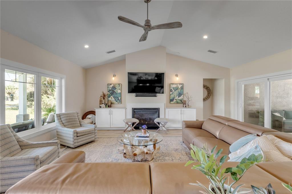 A living room features a vaulted ceiling, fireplace, television, and tan leather sectional sofa — 2760 PEARL LAKE TRAIL, NEW SMYRNA BEACH, FL