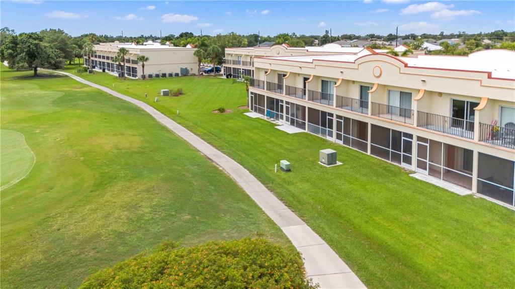 An aerial view shows two multi-story apartment buildings with a shared swimming pool and parking — 1186 RIO DE JANEIRO AVENUE UNIT 104, PUNTA GORDA, FL