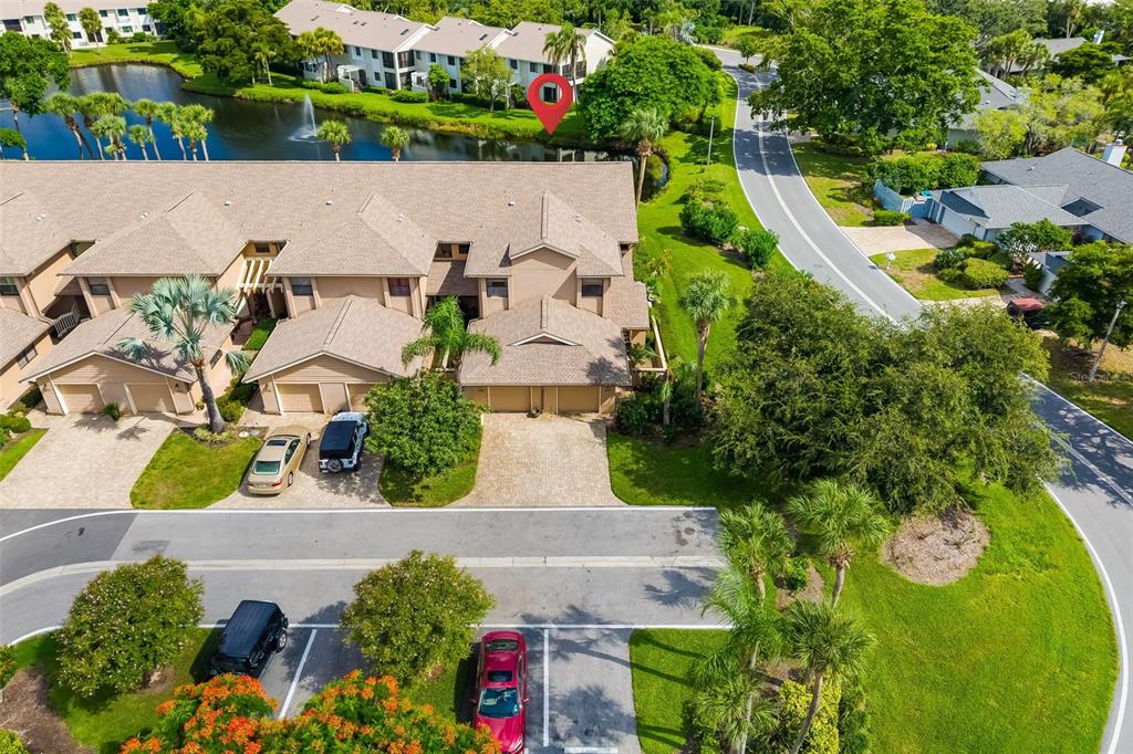 An aerial view shows a multi-unit townhouse complex with a pond and paved parking — 5287 HERON WAY UNIT 205, SARASOTA, FL