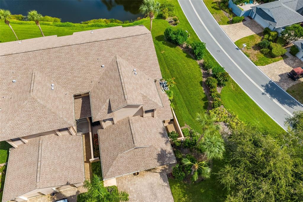 An aerial view shows a residential building with a shingled roof near a road — 5287 HERON WAY UNIT 205, SARASOTA, FL