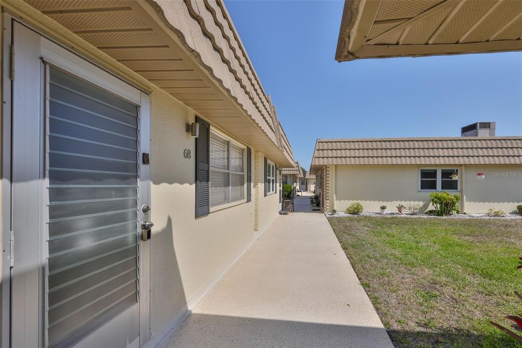 An exterior view of a single-story residential building with a concrete walkway and unit 68 — 202 BEDFORD STREET UNIT 68, SUN CITY CENTER, FL