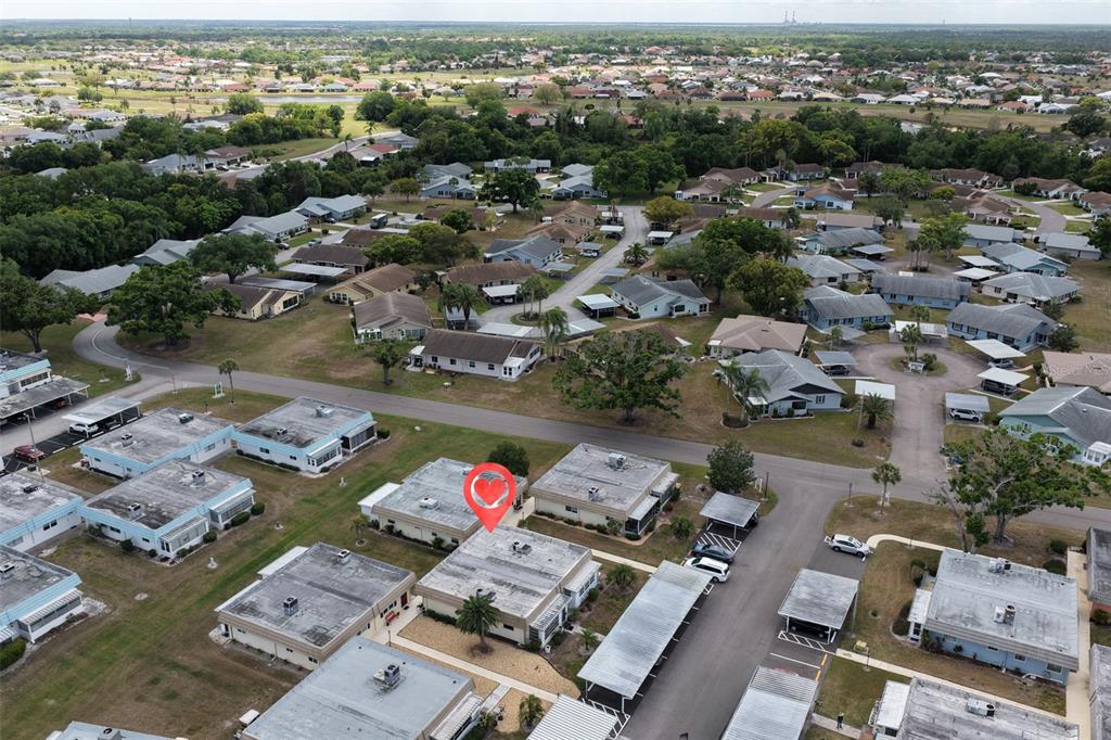 An aerial view shows a residential neighborhood with flat-roofed buildings and covered parking carports — 202 BEDFORD STREET UNIT 68, SUN CITY CENTER, FL