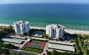 An aerial view shows two white residential buildings, a tennis court, and a swimming pool — 1050 LONGBOAT CLUB ROAD UNIT 804, LONGBOAT KEY, FL