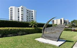 A stone monument stands on a grassy lawn in front of a tall apartment building — 1050 LONGBOAT CLUB ROAD UNIT 804, LONGBOAT KEY, FL