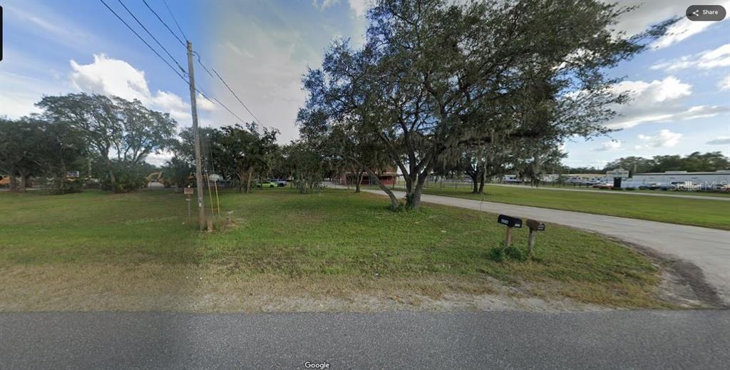A grassy, tree-filled vacant lot sits along a paved road with two mailboxes in front — N/A, POLK CITY, FL