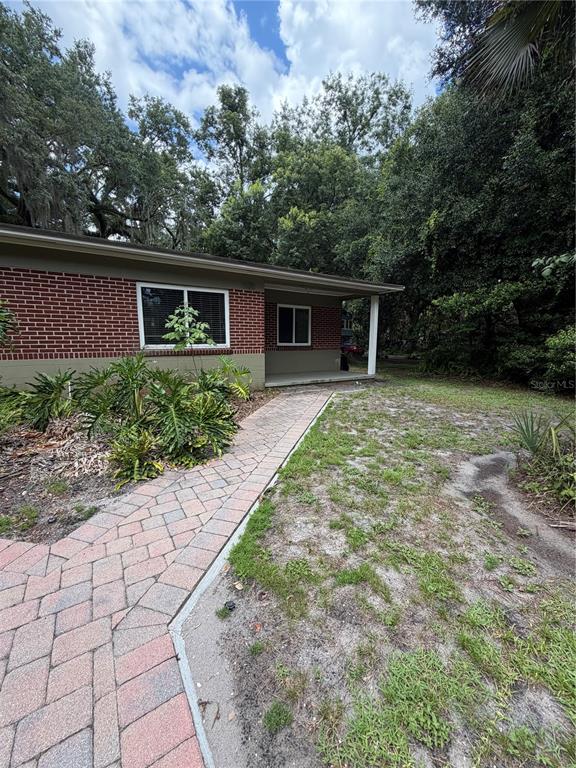 A brick house exterior features a paved walkway leading to a covered front porch — 1120 PALMER STREET, ORLANDO, FL