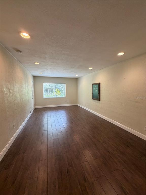 An empty room features dark wood-look flooring, recessed ceiling lights, and a single window — 1120 PALMER STREET, ORLANDO, FL