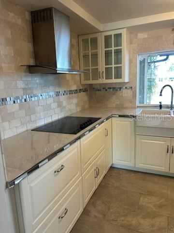 A kitchen features white cabinets, a stainless steel range hood, and a tiled backsplash — 3601 LANDALE DRIVE, HOLIDAY, FL
